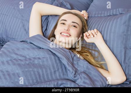 Close up sourire fille se réveillant sur le lit le matin Banque D'Images