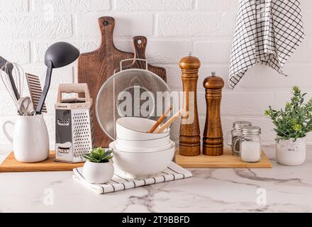 différents ustensiles et outils de cuisine en matériaux naturels sur un comptoir en pierre légère et plantes en pots vue de face. Cuisine écologique Banque D'Images