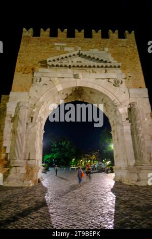 Arc d'Auguste de dessous dans la nuit, une porte dans l'ancien mur de la ville de Rimini, Italie, et les gens marchant Banque D'Images