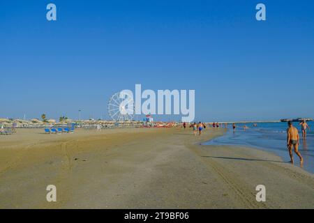 Juillet 2023 Rimini, Italie : Plage de Rimini à travers l'horizon et grande roue, et les gens ayant du plaisir Banque D'Images