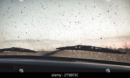 Gouttes de saleté sur le pare-brise d'une voiture. Paysage d'automne à travers le pare-brise d'une voiture Banque D'Images