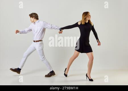 Les jeunes qui essaient d'aller dans des directions différentes, mais leurs mains sont attachées avec des chaînes de fer, des fers sur fond blanc de studio Banque D'Images