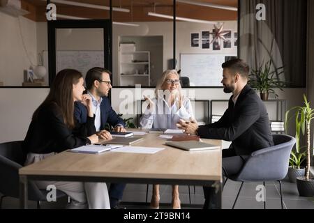 Femme propriétaire d'entreprise senior parlant à l'équipe de jeunes gestionnaires Banque D'Images