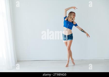 Mince femme blonde dansant dans une pièce lumineuse Banque D'Images