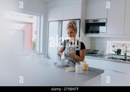 Young woman baking in kitchen Banque D'Images