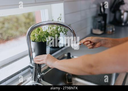 Les mains de la femme versant de l'eau dans la cuillère à mesurer Banque D'Images
