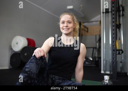 Portrait de jeune femme souriante assise au gymnase Banque D'Images