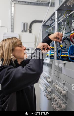 Technicien féminin vérifiant les câbles dans la salle de contrôle à l'industrie Banque D'Images
