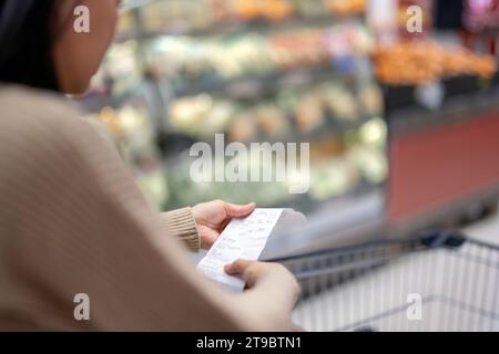 Femme examinant la liste de courses au supermarché Banque D'Images