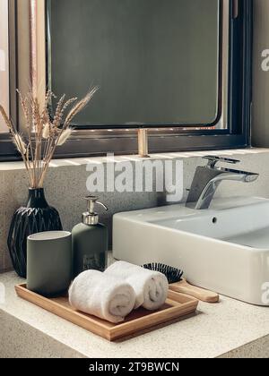 Deux essuie-mains dans la salle de bains avec distributeur de savon liquide sur plateau en bambou et brosse à cheveux Banque D'Images