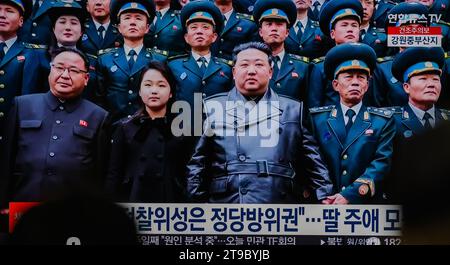 Les nouvelles télévisées à la gare de Yongsan à Séoul montrent le dirigeant nord-coréen Kim Jong un (C) et sa fille (2e de L, première rangée), qui se prénommerait Kim Ju AE, posant pour une photo avec des scientifiques et des ingénieurs qui ont contribué au dernier lancement d'un satellite de reconnaissance dans le pays, alors qu'il visitait l'Administration nationale des technologies aérospatiales à Pyongyang. Le dirigeant nord-coréen Kim Jong-un a salué le lancement réussi par le pays d'un satellite de reconnaissance comme un événement révélateur du déploiement d'une « garde spatiale » surveillant les activités militaires ennemies, ont rapporté les médias d'État le 24 novembre. K Banque D'Images