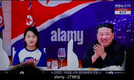 Les nouvelles télévisées de la gare de Yongsan à Séoul montrent le dirigeant nord-coréen Kim Jong un (à droite) et sa fille (à gauche), soupçonnée d'être nommée Kim Ju AE, assister à un banquet pour célébrer le lancement réussi par le pays d'un satellite de reconnaissance. Le dirigeant nord-coréen Kim Jong-un a salué le lancement réussi par le pays d'un satellite de reconnaissance comme un événement révélateur du déploiement d'une « garde spatiale » surveillant les activités militaires ennemies, ont rapporté les médias d'État le 24 novembre. Kim a fait cette remarque lors de sa visite à la National Aerospace Technology Administration (NATA) le 23 novembre, comme il l'a encouragé Banque D'Images