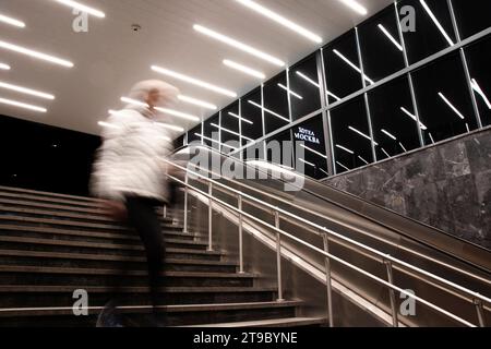 Belgrade, Serbie- 20 novembre 2023 : personne floue descendant les escaliers du métro avec des reflets de lumières intérieures et le panneau de l'hôtel Moscou en cyrillique Banque D'Images