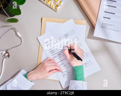 Vue de dessus médecin méconnaissable prenant des notes dans la documentation médicale à la clinique Banque D'Images