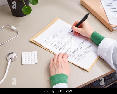 Vue de dessus médecin méconnaissable prenant des notes dans la documentation médicale à la clinique Banque D'Images