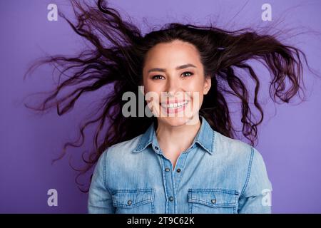 Portrait de fille folle joyée débordant de sourire volant cheveux désordonnés isolé sur fond de couleur violette Banque D'Images