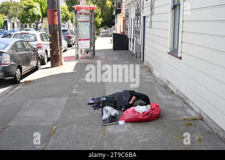 San Francisco, CA, USA - 26 juillet 2023 : un homme sans abri dort dans la rue dans le centre-ville de San Francisco. Banque D'Images