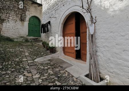 070 Vieille porte en bois incolore, à double vantail rond sur mur de pierre, rue Rruga Kristaq Tutulani, quartier de Gorica. Berat-Albanie. Banque D'Images