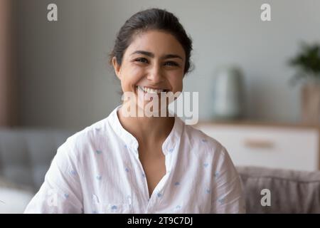 Femme indienne heureuse assis sur le canapé sourire regarder la caméra Banque D'Images