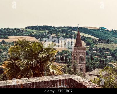 Tranquillité sacrée encadrée par la grandeur de la nature : une tour d'église se dresse haut, embrassé par la présence gracieuse d'un palmier au premier plan, tandis que Banque D'Images