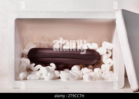 Boîte cadeau noire dans la boîte de polystyrène avec des arachides d'emballage, événement de célébration, Banque D'Images