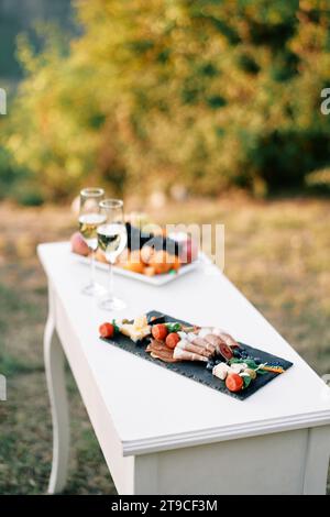 Petite table de fête avec deux verres de champagne et des collations se tient sur la pelouse Banque D'Images