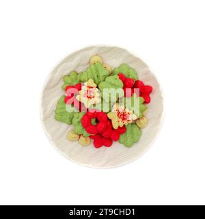 Plateau rond rempli de biscuits spritz de noël en rouge, vert et blanc avec du sucre de ponçage rouge en forme d'arbre, d'ornement et de fleur de poinsettia Banque D'Images