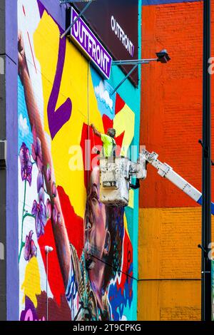 Sur une riser, un artiste commercial peint un mur de maison à Detroit, aux États-Unis : This Wall atteint le public Banque D'Images