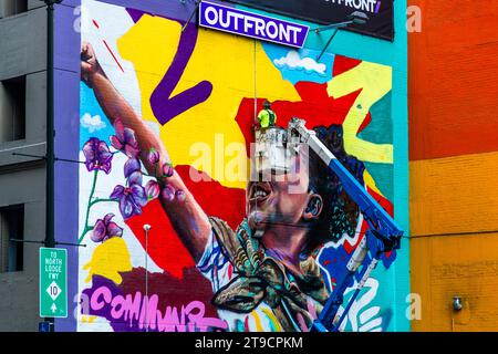 Street art à Detroit. Un travailleur dans un transpalette ressemble à une partie tridimensionnelle du mur peint de la maison. Sur une riser, un artiste commercial peint un mur de maison à Detroit, aux États-Unis : This Wall atteint le public Banque D'Images