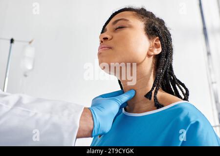 malade jolie femme afro-américaine fermant les yeux pendant que son médecin indien examine ses ganglions lymphatiques Banque D'Images