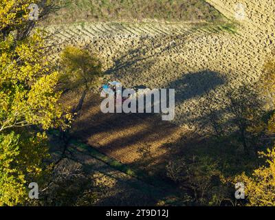 Tracteur rampé labourer le sol aride sec sur la colline de la vallée d'Arda, en Italie, pour semer le blé pendant la saison d'automne en novembre Banque D'Images