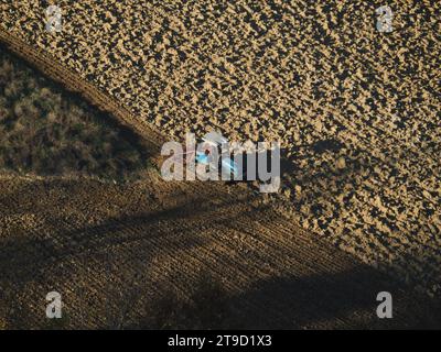 Tracteur rampé labourer le sol aride sec sur la colline de la vallée d'Arda, en Italie, pour semer le blé pendant la saison d'automne en novembre Banque D'Images