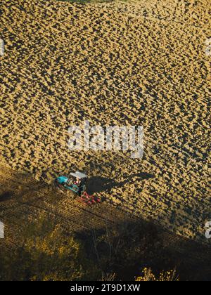 Tracteur rampé labourer le sol aride sec sur la colline de la vallée d'Arda, en Italie, pour semer le blé pendant la saison d'automne en novembre Banque D'Images