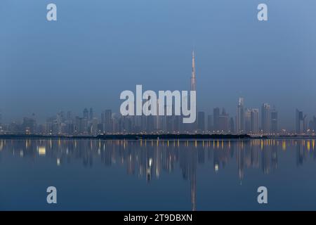 Paysage d'horizon du centre-ville de Dubaï la nuit avec des bâtiments illuminés et des reflets dans l'eau de Dubai Creek, des couleurs froides, vu depuis le port de Dubai Creek Banque D'Images