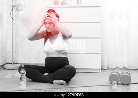 Young pregnant woman feel bad during her fitness workout at home Stock Photo