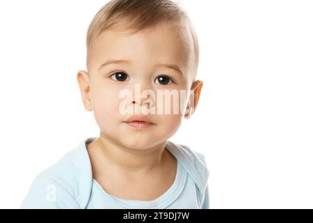 Gros plan d'un visage curieux d'un adorable petit garçon dans une barboteuse sur fond blanc. Banque D'Images