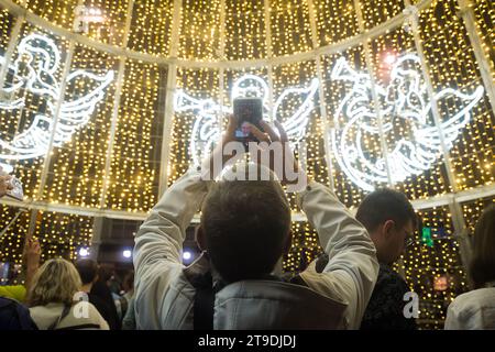 Malaga, Espagne. 24 novembre 2023. Un homme est vu prendre des photos à l'intérieur d'un arbre de Noël pendant l'allumage de l'éclairage de Noël sur la place Plaza de la Constitucion. Chaque année, la ville de Malaga allume ses lumières de Noël pour marquer le début de la saison de Noël, où des milliers de personnes se rassemblent dans le centre-ville pour voir une nouvelle décoration de Noël et des spectacles de lumière. Selon le site Web European Best destination, Malaga ville a l'un des meilleurs éclairage de Noël en Europe. Crédit : SOPA Images Limited/Alamy Live News Banque D'Images