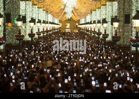 Malaga, Espagne. 24 novembre 2023. Vue générale des personnes utilisant leur téléphone portable en regardant les lumières de Noël dans la rue marques de Larios. Chaque année, la ville de Malaga allume ses lumières de Noël pour marquer le début de la saison de Noël, où des milliers de personnes se rassemblent dans le centre-ville pour voir une nouvelle décoration de Noël et des spectacles de lumière. Selon le site Web European Best destination, Malaga ville a l'un des meilleurs éclairage de Noël en Europe. Crédit : SOPA Images Limited/Alamy Live News Banque D'Images