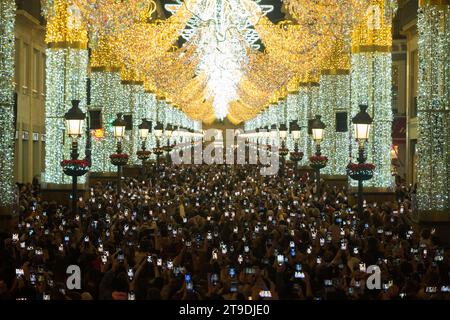 Malaga, Espagne. 24 novembre 2023. Vue générale des personnes utilisant leur téléphone portable en regardant les lumières de Noël dans la rue marques de Larios. Chaque année, la ville de Malaga allume ses lumières de Noël pour marquer le début de la saison de Noël, où des milliers de personnes se rassemblent dans le centre-ville pour voir une nouvelle décoration de Noël et des spectacles de lumière. Selon le site Web European Best destination, Malaga ville a l'un des meilleurs éclairage de Noël en Europe. Crédit : SOPA Images Limited/Alamy Live News Banque D'Images