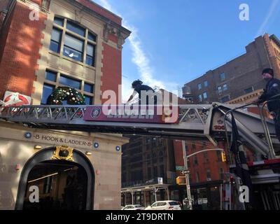 New York, New York, États-Unis. 24 novembre 2023. Qui vas-tu appeler ? Les pompiers de Ladder 8 Tribeca NYC, la caserne de pompiers de Ghostbusters, mettent en place leurs décorations de Noël annuelles en utilisant leur échelle de camion de pompiers. Le célèbre Ghostbusters Firehouse est un meca pour les touristes et une véritable compagnie d'échelle NYFD desservant le centre-ville de New York. (Image de crédit : © Milo Hess/ZUMA Press Wire) USAGE ÉDITORIAL SEULEMENT! Non destiné à UN USAGE commercial ! Banque D'Images