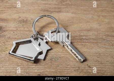 Clé avec porte-clés en forme de maison sur table en bois, closeup Banque D'Images