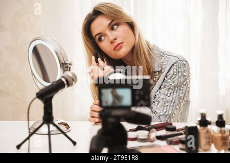 Jeune femme blogueuse de beauté utilisant le gel de teinte de sourcil pendant l'enregistrement vidéo pour ses followers Banque D'Images