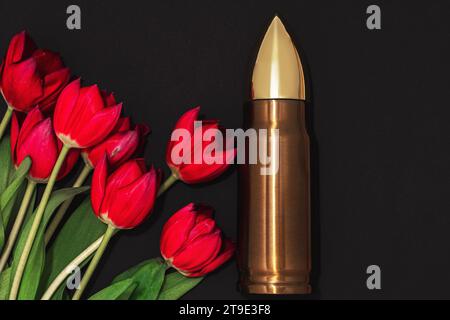 Pacifisme, mouvement de non-violence ou jour de la victoire. Grosse balle et bouquet de tulipes rouges. Banque D'Images