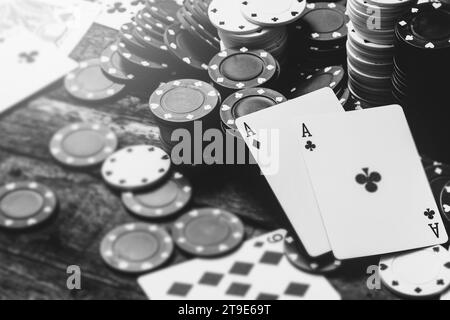 Image monochrome de deux as et beaucoup de jetons de casino sur la table en bois Banque D'Images