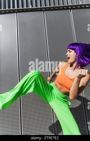 Danseuse active insouciante portant des vêtements de sport colorés s'amusant dans la rue pendant la journée ensoleillée d'été Banque D'Images