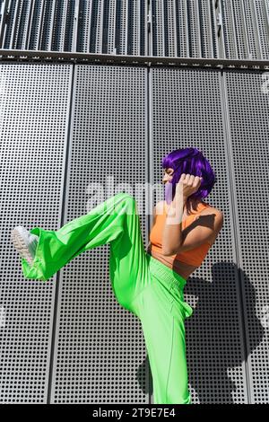 Danseuse active insouciante portant des vêtements de sport colorés s'amusant dans la rue pendant la journée ensoleillée d'été Banque D'Images