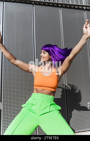 Danseuse active insouciante portant des vêtements de sport colorés s'amusant dans la rue pendant la journée ensoleillée d'été Banque D'Images