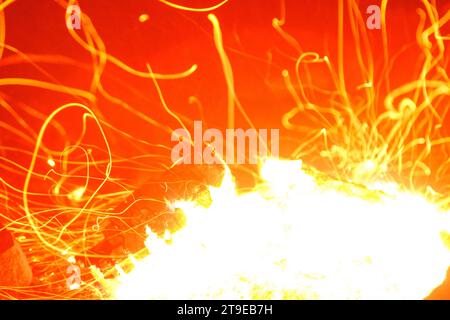 Gros plan d'un feu de camp brûlant brillamment la nuit et jetant des étincelles autour. Banque D'Images