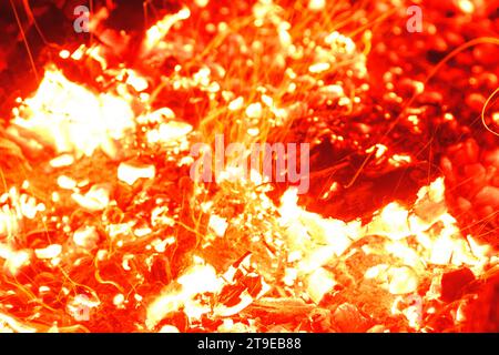Gros plan d'un feu de camp brûlant brillamment la nuit et jetant des étincelles autour. Banque D'Images