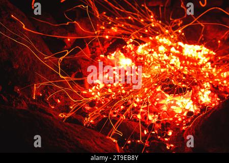 Gros plan d'un feu de camp brûlant brillamment la nuit et jetant des étincelles autour. Banque D'Images